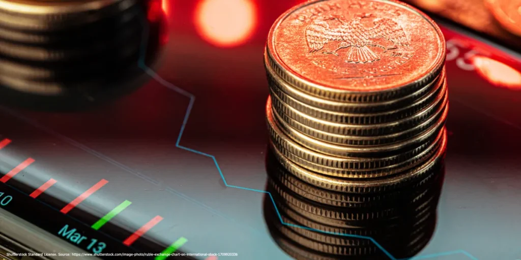 Stacked coins sit on a digital financial chart with red and green market indicators.