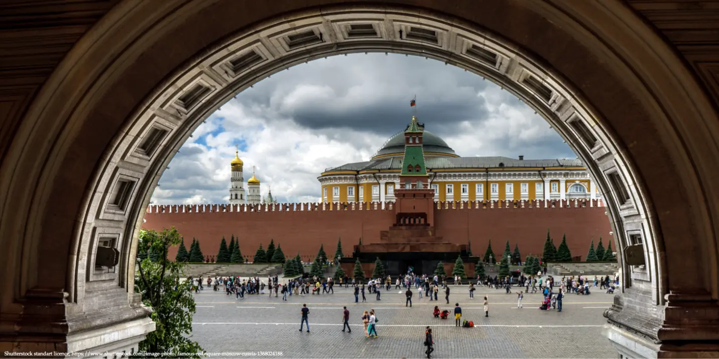 Kremlin view framed by a historic arch with a crowd in Moscow, symbolizing the impact of the Iran Crisis on Russia’s oil.